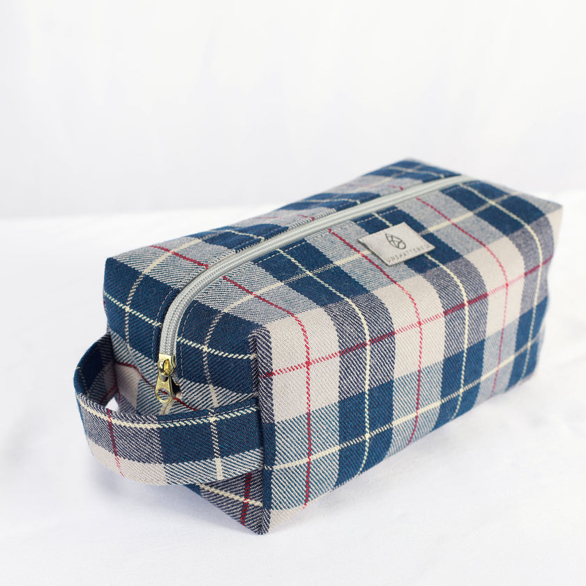 A gold tone zipper on a blue mercedes Benz fabric toiletry kit 