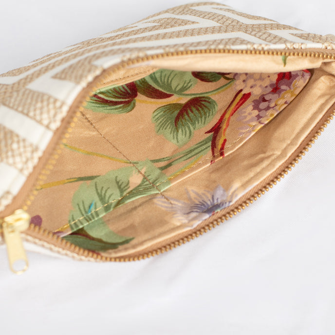 A beige flower interior fabric on a white and tan lined wristlet with gold hardware 