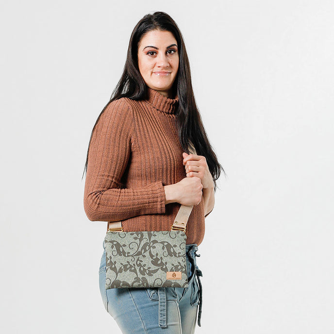 A woman carrying a green floral  patterned crossbody bag with a beige strap named after Mikaley
