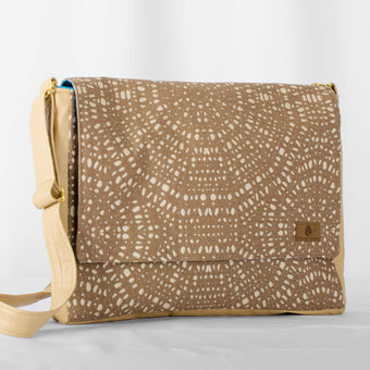 A large messenger bag with an adjustable strap and a beige and brown patterned fabric. It features gold strap slides and a magnetic clasp.