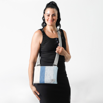 woman wearing a multicolored blue and white crossbody  bag with a gray strap on a white background named after Mo 