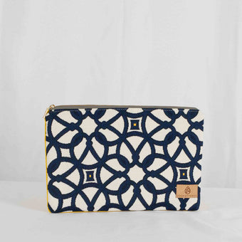 A large zip pouch with a geometric pattern in blue and white, and a yellow sidewall, with a brand tag displaying Unshattered 