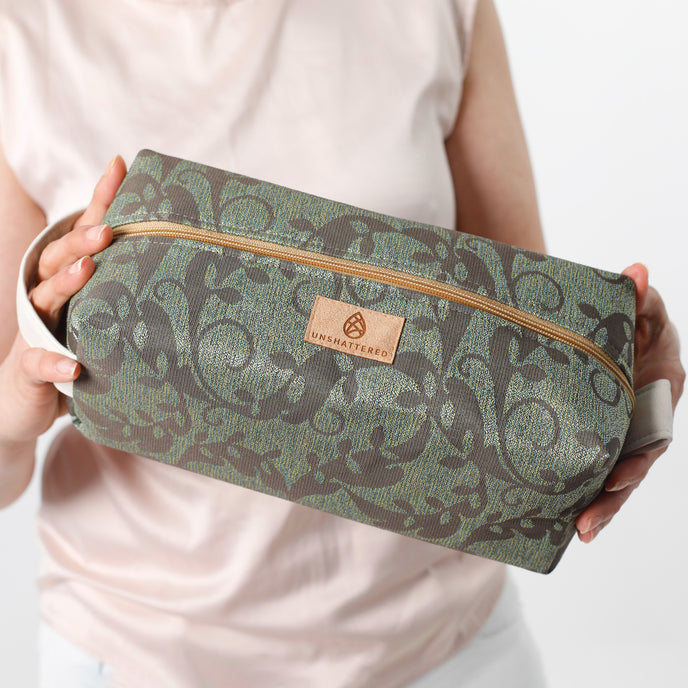 Person holding a green patterned toiletry bag
