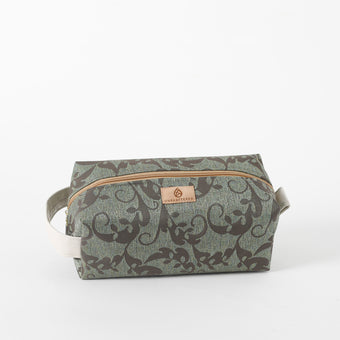 A green and brown geometric patterned toiletry kit with a white zipper and a brand tag 
