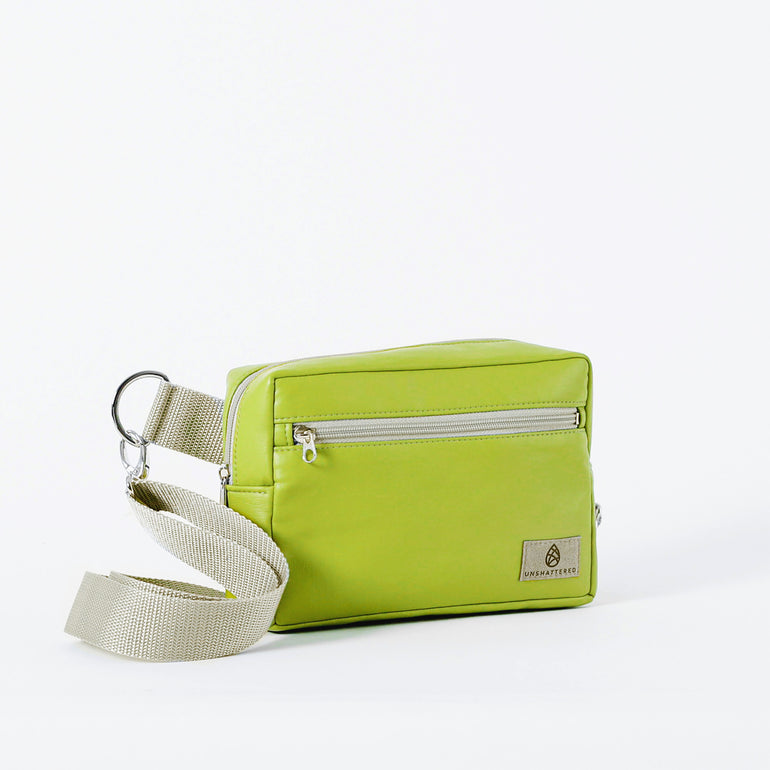 A vibrant lime green crossbody errand bag with zipper closure, an adjustable strap, and a silver-tone hardware, handcrafted from upcycled materials, bag named after Nadine.