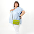 A woman wearing a lime green errand bag crossbody style worn named after Nadine 
