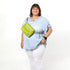 A woman wearing a lime green errand bag across her chest smiling, bag named after Nadine 