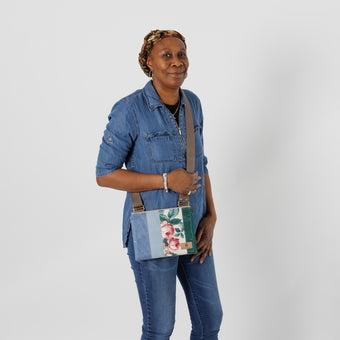 A woman wearing a flower crossbody with multi-panel blue, and green with a brown strap named after Nadiya 
