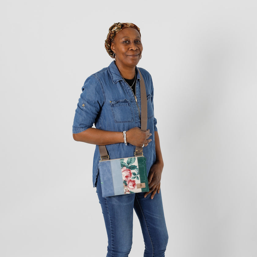 A woman wearing a flower crossbody with multi-panel blue, and green with a brown strap named after Nadiya 