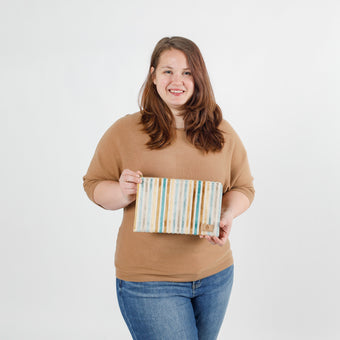 Woman holding a striped large zip pouch against a white background