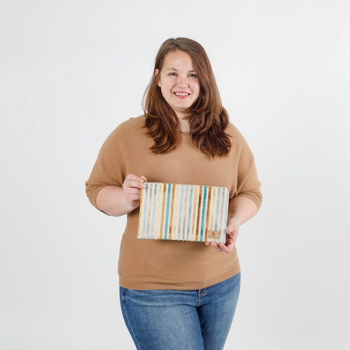 Woman holding a striped large zip pouch against a white background