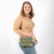 A woman wearing a Nicole Crossbody bag with geometric pattern and beige strap on a white background 