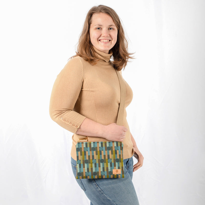 A woman wearing a Nicole Crossbody bag with geometric pattern and beige strap on a white background 