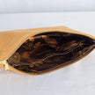 A floral brown interior fabric on a tan suede large zip pouch with a gold tone zipper