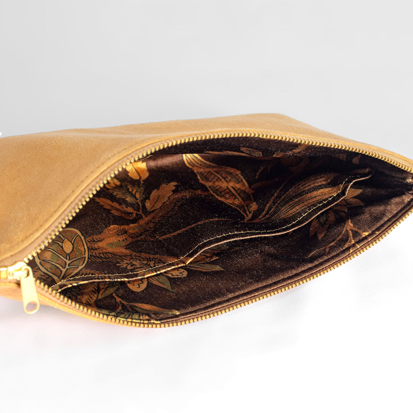 A floral brown interior fabric on a tan suede large zip pouch with a gold tone zipper