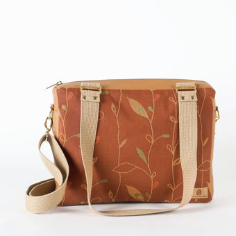 Brown bag with leaf pattern and beige strap on a white background