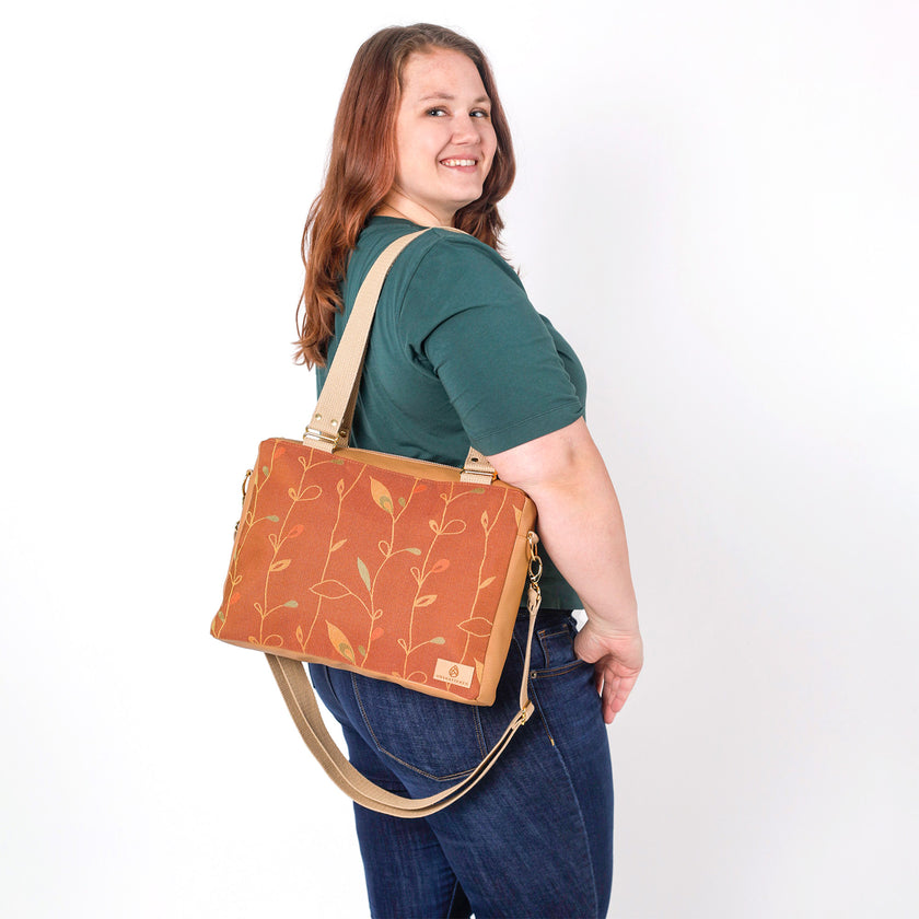 Woman carrying a brown bag with floral design on a white background named after Nita 