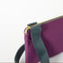 A gray strap with gold hardware on a purple crossbody named after Nora 