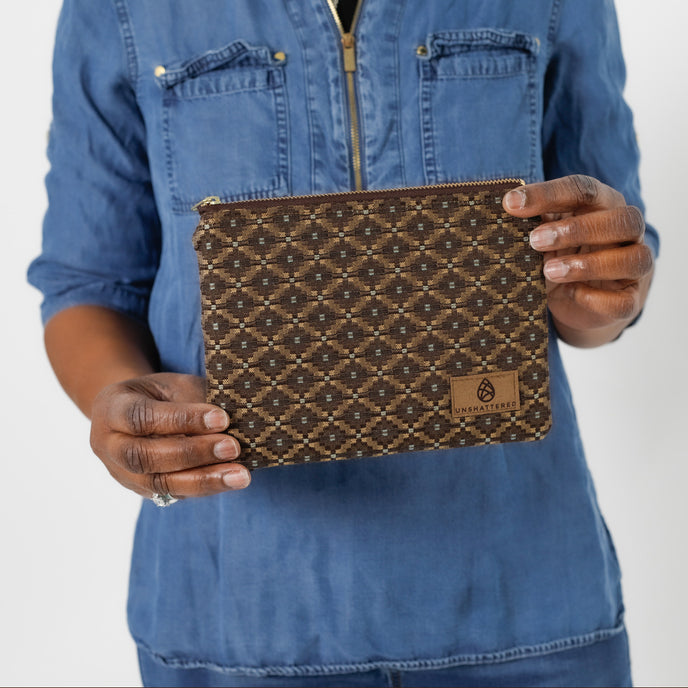 Hands holding a brown zip pouch with blue squares in the fabric named after Norma