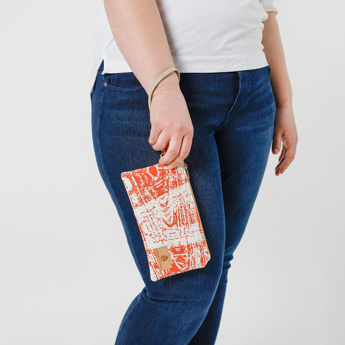 Person holding a orange and white wristlet on her wrist  against a white background