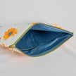 A blue fabric with dots interior on this large white sunflower design zip pouch 