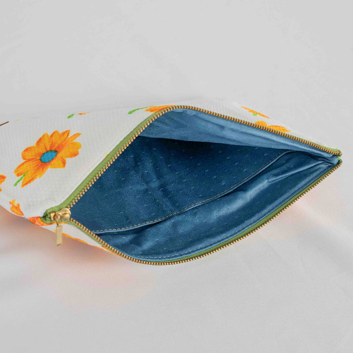 A blue fabric with dots interior on this large white sunflower design zip pouch 