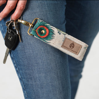 A woman wearing jeans holding peacock fabric key clip with keys named after Eliza