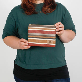 A woman holding a fall colored striped zip pouch named after Peanut