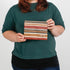 A woman holding a fall colored striped zip pouch named after Peanut