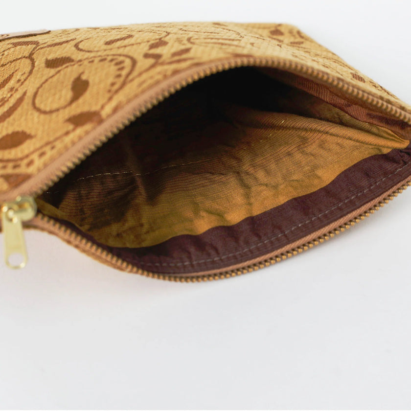 Open zip pouch with tan leaf pattern and gold hardware on a white background