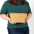 A woman holding a yellow design pattern makeup bag named after Priscilla 