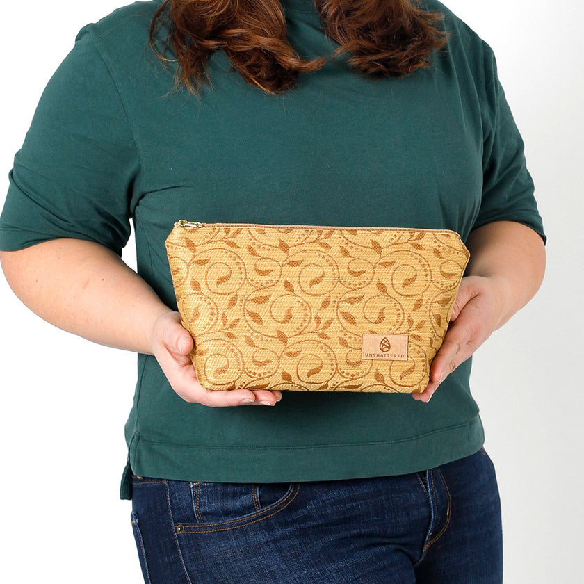 A woman holding a yellow design pattern makeup bag named after Priscilla 