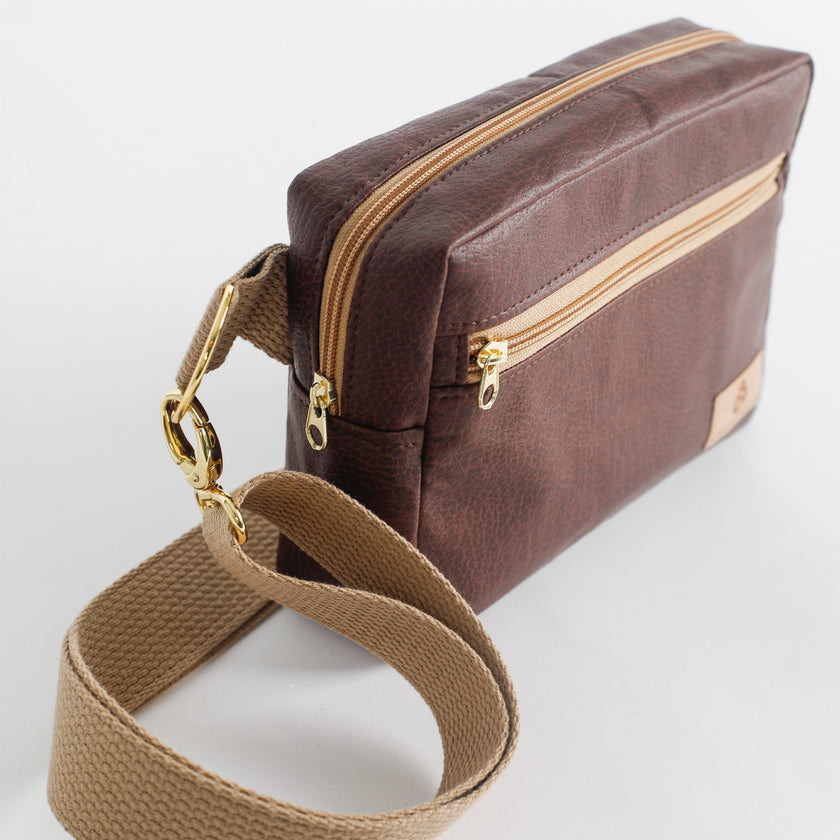 Brown errand bag with gold-tone zipper and tan cotton strap on a white background named after Priscilla.