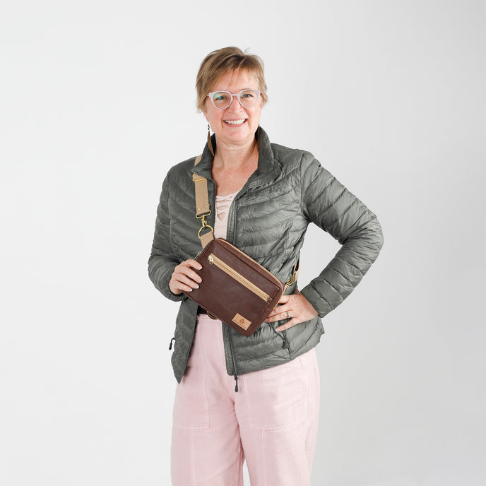 Woman holding a brown vegan leather bag against a white background named after Priscilla