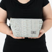 A woman holding a blue pattern design makeup kit named after Rebecca