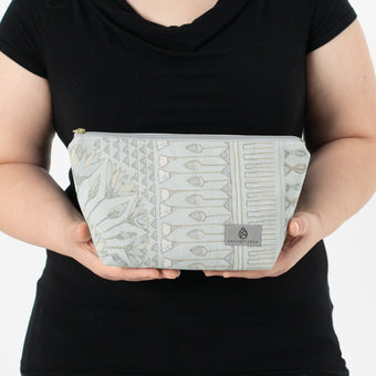 A woman holding a blue pattern design makeup kit named after Rebecca