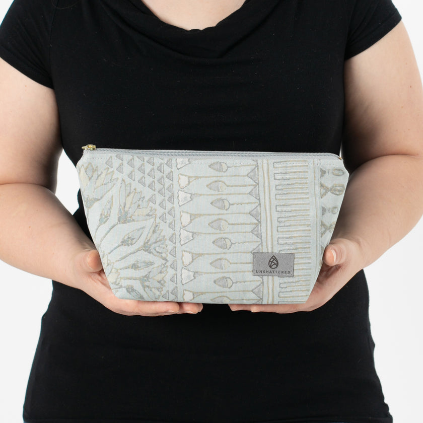 A woman holding a blue pattern design makeup kit named after Rebecca