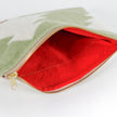 Red upcycled fabric interior of a green woolen pouch with a white Christmas tree pattern on a white background