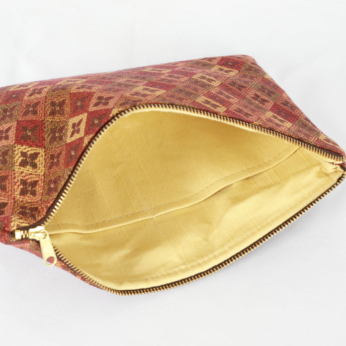 A yellow fabric interior with a gold tone zipper on a fall color large zip pouch 