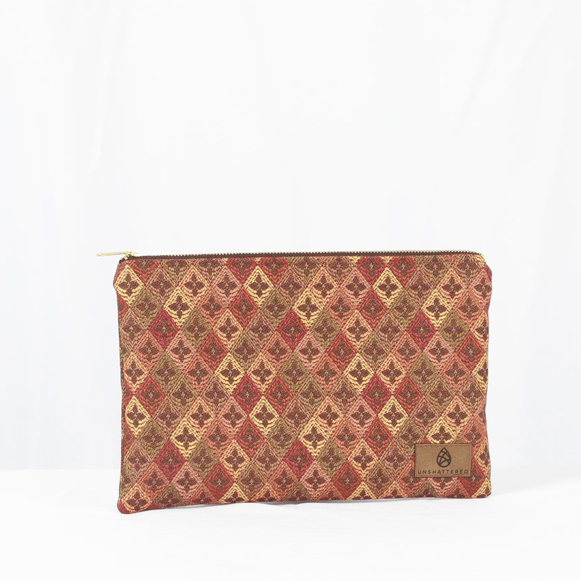 A large zip pouch with a red and beige diamond pattern and a visible brand logo on the lower right corner.