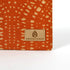 Orange fabric with a pattern zip pouch and 'Unshattered' brand label on a white background named after Rena 