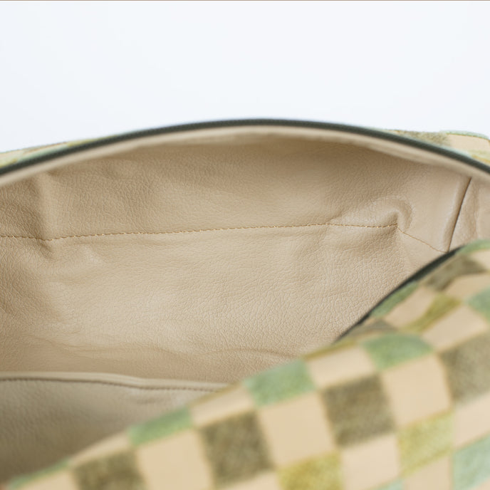 A close-up view of a cream-colored luxury leather alternative interior featuring elegant gold-toned stitching, showcased inside a checkered pattern upcycled toiletry bag.