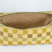 A tan luxury leather alternative material on this beige and green checkered toiletry kit 