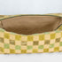 A tan luxury leather alternative material on this beige and green checkered toiletry kit 