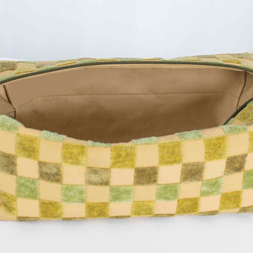 A tan luxury leather alternative material on this beige and green checkered toiletry kit 