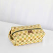 A  toiletry kit with a checkered pattern in green and tan colors, featuring a zip closure and gold-tone hardware.