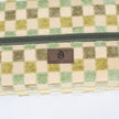 A close-up, detailed shot of a brown Unshattered brand label stitched onto the exterior of a stylish, upcycled checkered toiletry bag, showcasing the brand’s commitment to quality craftsmanship and sustainable material design.