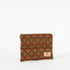 A geometric patterned zip pouch in autumnal colors with a prominent brown X pattern, featuring a small brand tag on the bottom right.