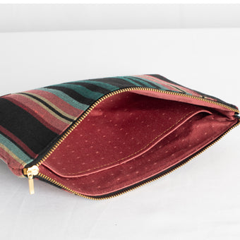 A mauve fabric with dots on theinteriror of a black striped large zip pouch 