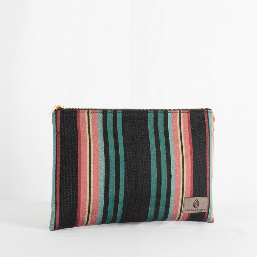 A striped fabric zip pouch with gold-tone hardware, upcycled material, and a brand label visible.